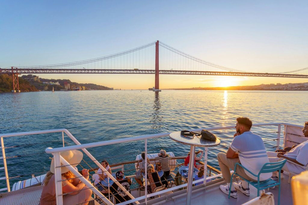 Cruzeiro ao pôr do sol no rio Tejo em Lisboa com bebidas e petiscos